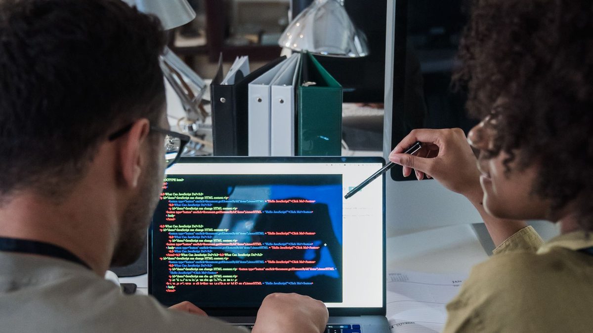 Two developers discussing software together on a laptop