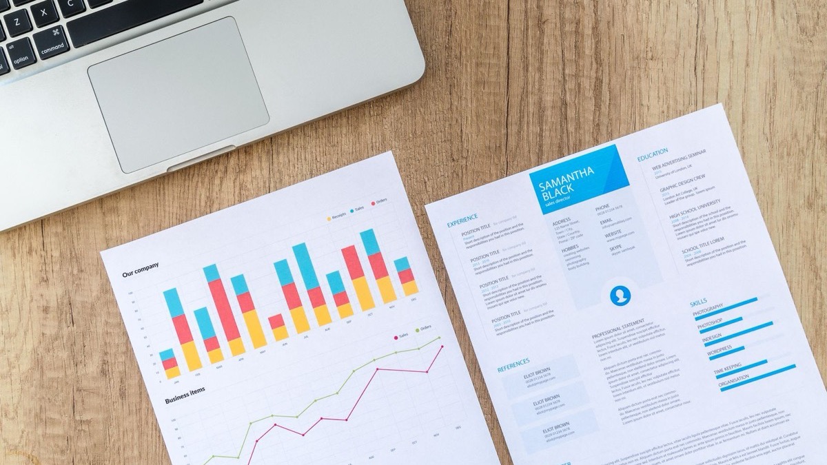 Printed charts and documents laid out next to a laptop on a desk during a project review