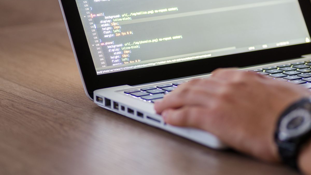 A developer working on application source code on a laptop, representing secure coding against the OWASP Mobile Top 10